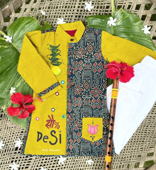 Kids traditional outfit showing a mustard yellow and indigo blue Ajrakh print kurta with handpainted mirror work, nimbu-mirchi illustration, 100% DeSi text, and white pyjamas.