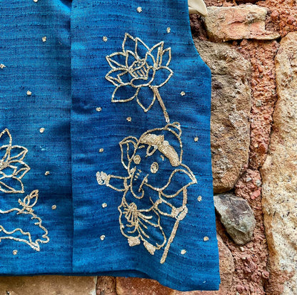 Kids traditional festive wear showing a premium royal teal blue handloom cotton sleeveless Bundi jacket for boys featuring intricate gold zardosi hand embroidery of a cute baby Lord Ganesha and lotus motifs.