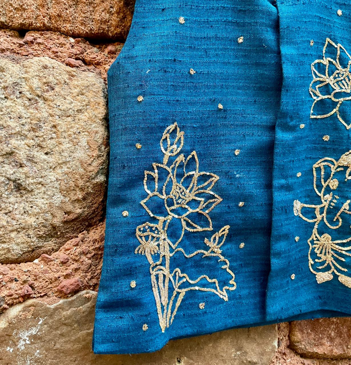 Kids traditional festive wear showing a premium royal teal blue handloom cotton sleeveless Bundi jacket for boys featuring intricate gold zardosi hand embroidery of a cute baby Lord Ganesha and lotus motifs.