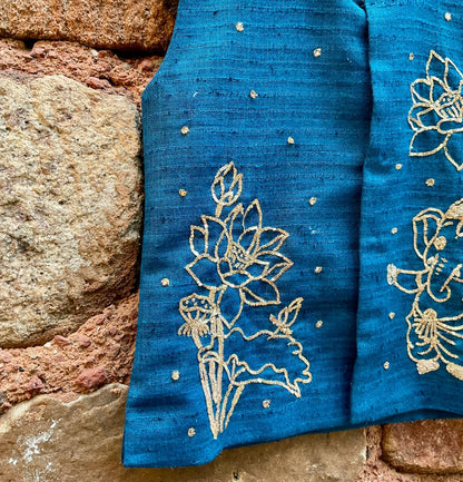 Kids traditional festive wear showing a premium royal teal blue handloom cotton sleeveless Bundi jacket for boys featuring intricate gold zardosi hand embroidery of a cute baby Lord Ganesha and lotus motifs.