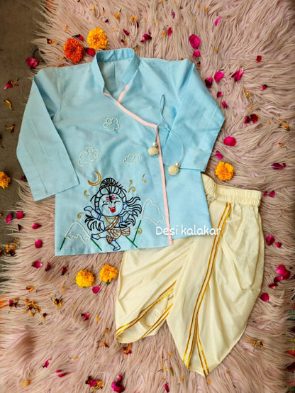 Little boy wearing a sky blue hand-embroidered Shiva Angrakha kurta with cream-colored dhoti pants."