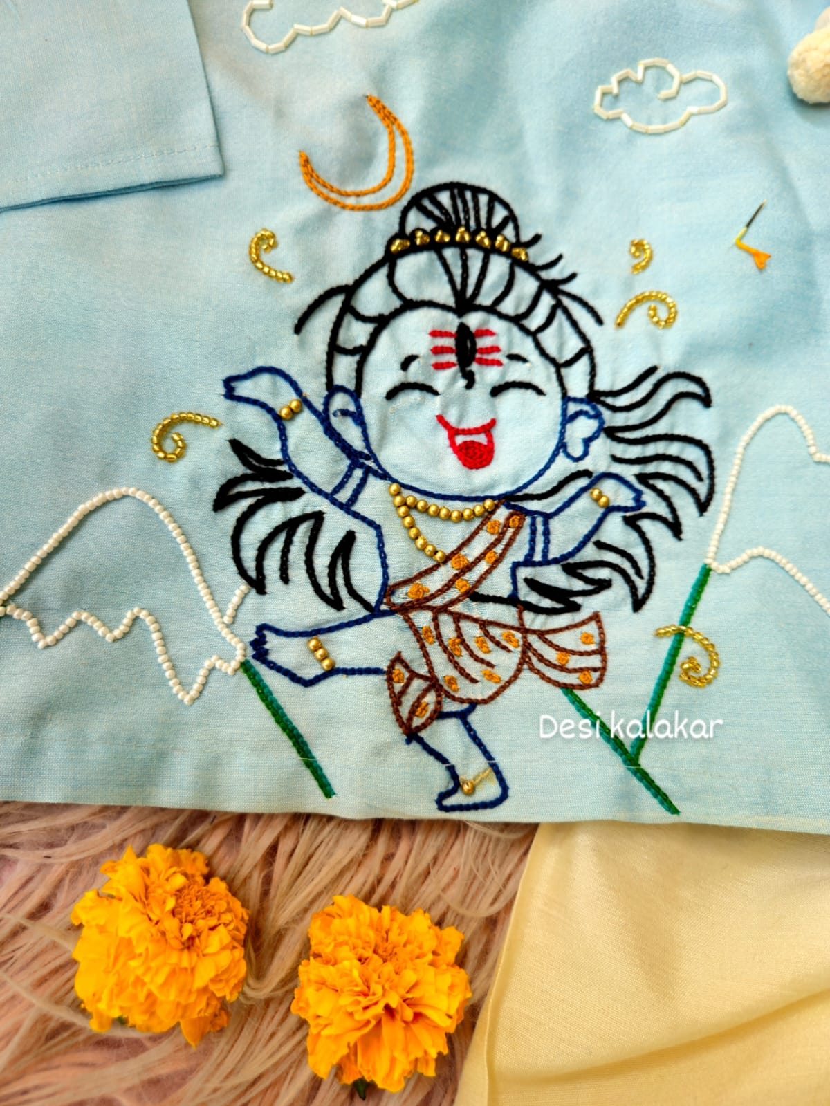 Little boy wearing a sky blue hand-embroidered Shiva Angrakha kurta with cream-colored dhoti pants."
