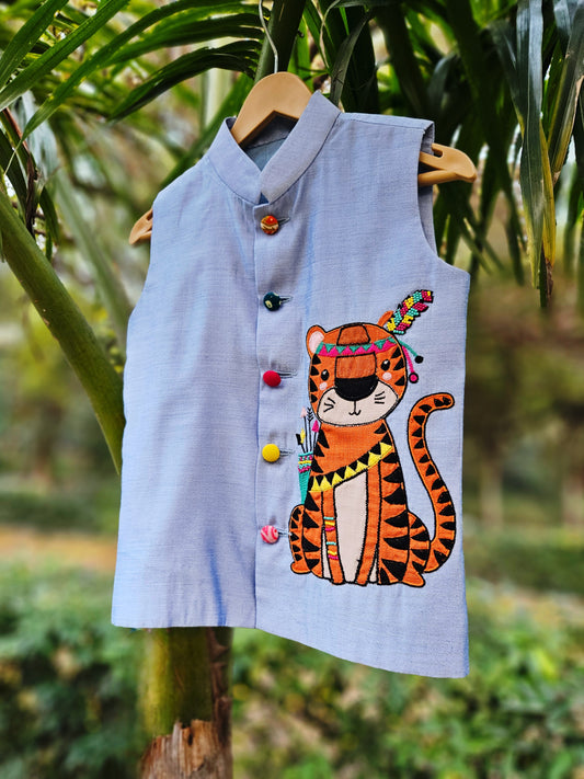 "Premium powder blue handcrafted Bundi Nehru jacket for boys featuring a large hand-embroidered tribal tiger motif with a colorful feather headpiece."