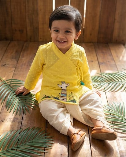 Baby boy wearing sunshine yellow cotton angrakha kurta with hand embroidered giraffe motif and off-white dhoti
