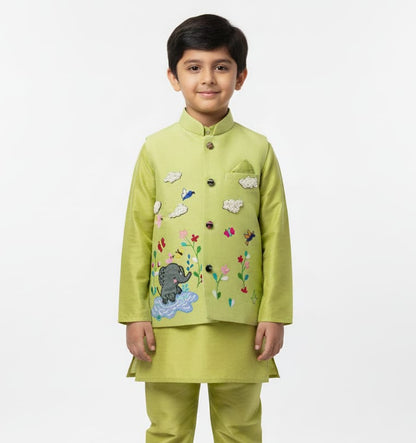 A boys' sleeveless pistachio-green ethnic Bundi jacket hanging on a wooden hanger, featuring hand-embroidered flowers, birds, butterflies, a baby elephant playing in water, and 3D beaded clouds.