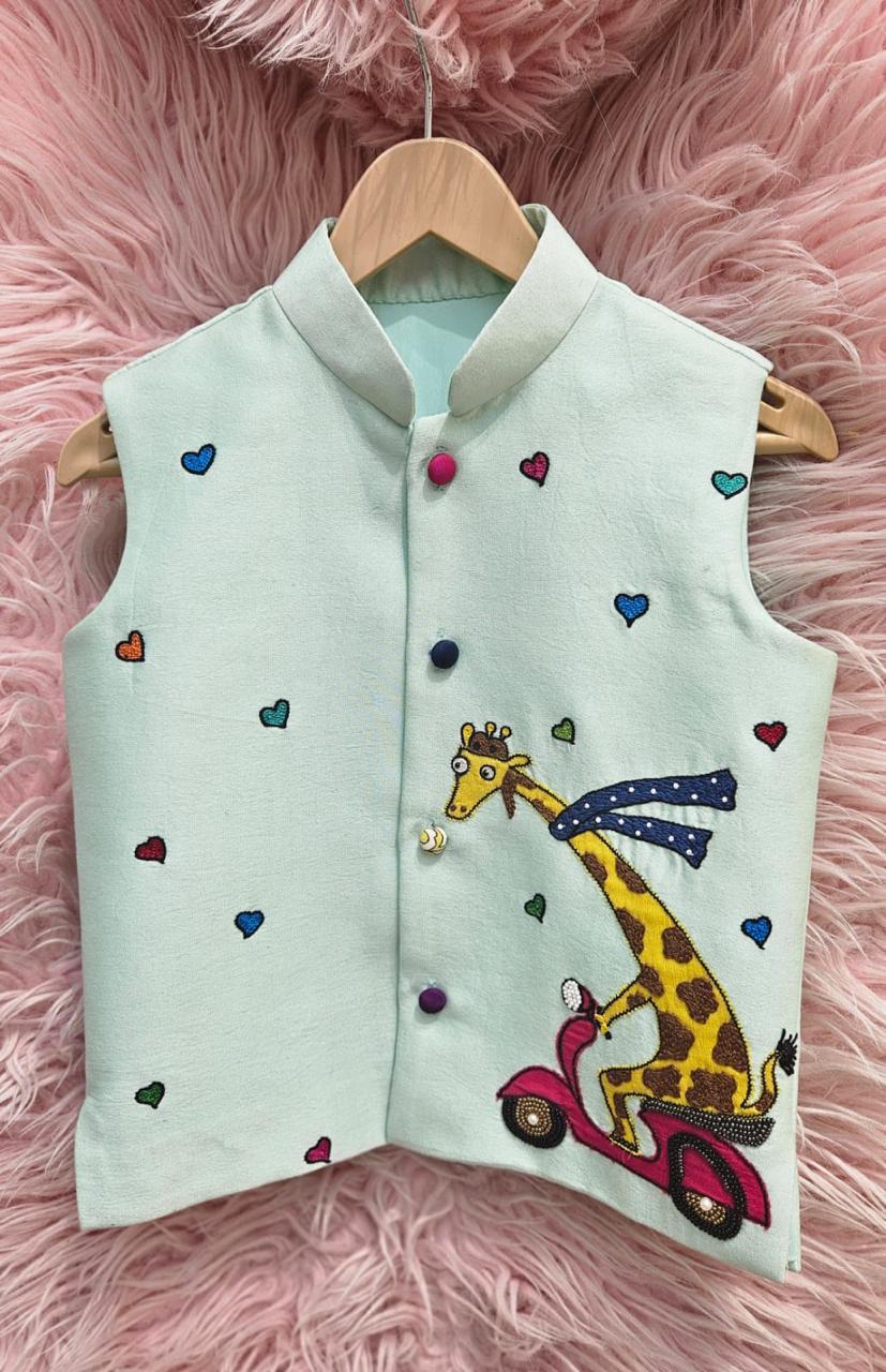 A mint green sleeveless ethnic Nehru jacket for kids hanging on a wooden hanger, featuring detailed hand-embroidery of a giraffe riding a pink scooter surrounded by tiny colorful hearts.