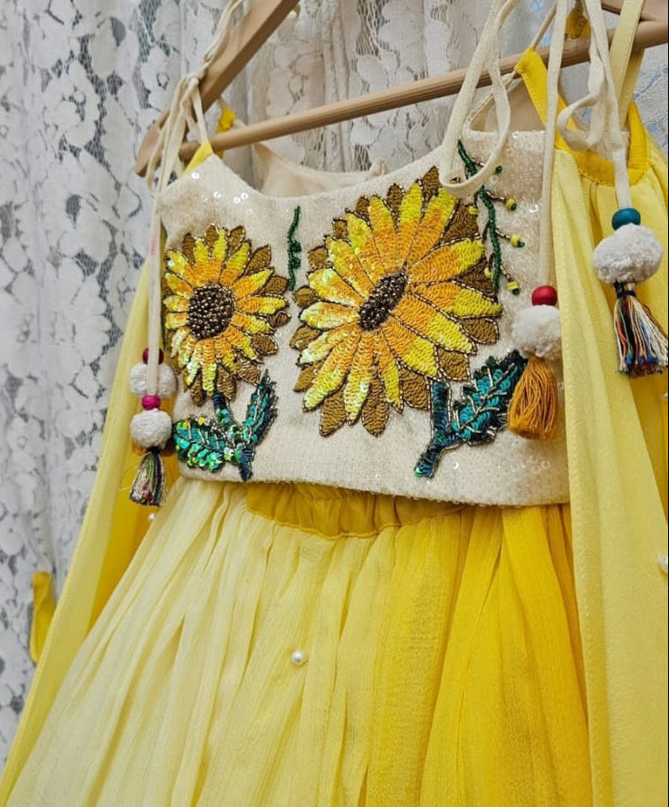 Sunshine yellow handcrafted sunflower motif blouse and pearl-accented flared lehenga set for girls by Desi Kalakar.